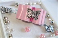 Papillon en métal et rocailles en dessous.
