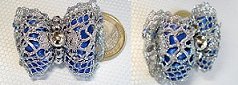 Ruban métallique léger entourant le ruban satin. Perles en métal argenté.