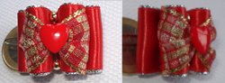 Un petit coeur rouge, en dessous du drapén rocailles et deux en métal doré.